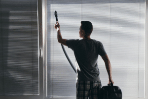 Man steam vacuum cleaning window blinds